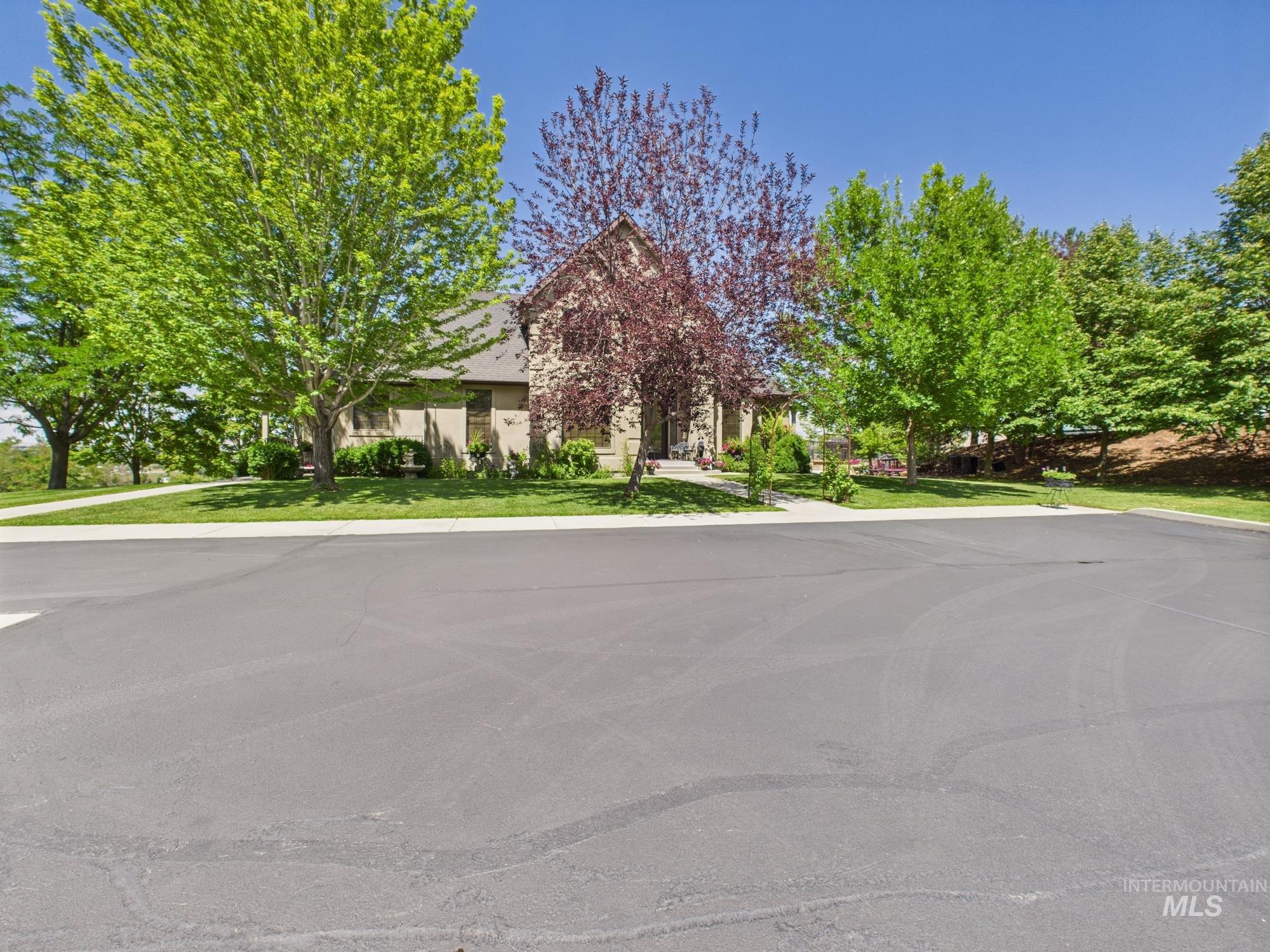 View of property hidden behind natural elements with stucco siding and a front yard