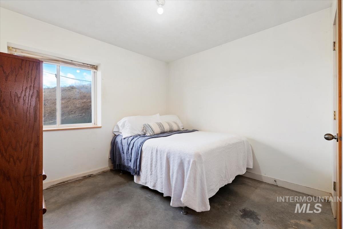 Bedroom featuring concrete floors and baseboards