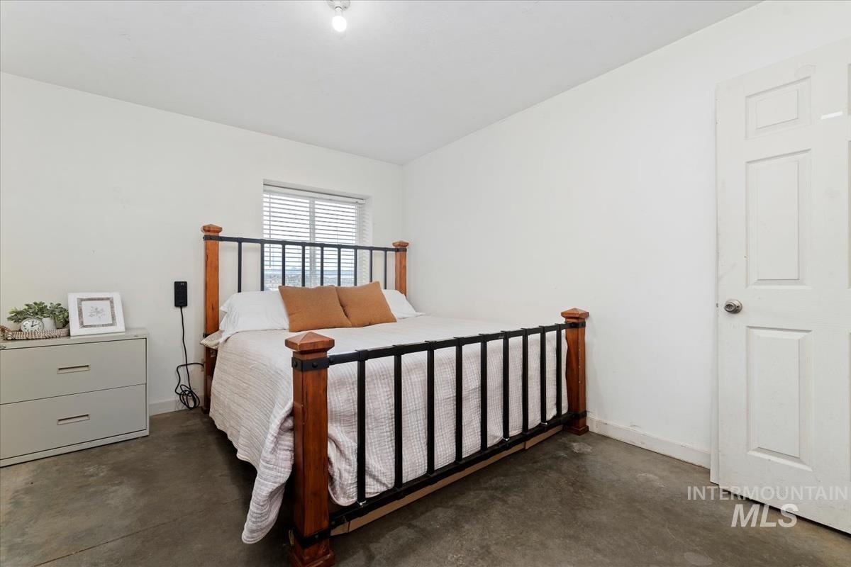 Bedroom with concrete floors and baseboards