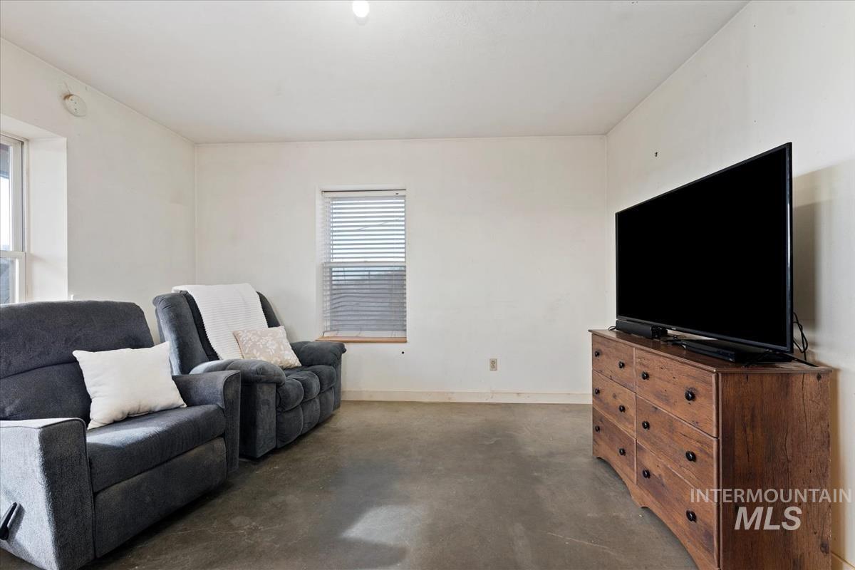 Living area featuring concrete floors and baseboards