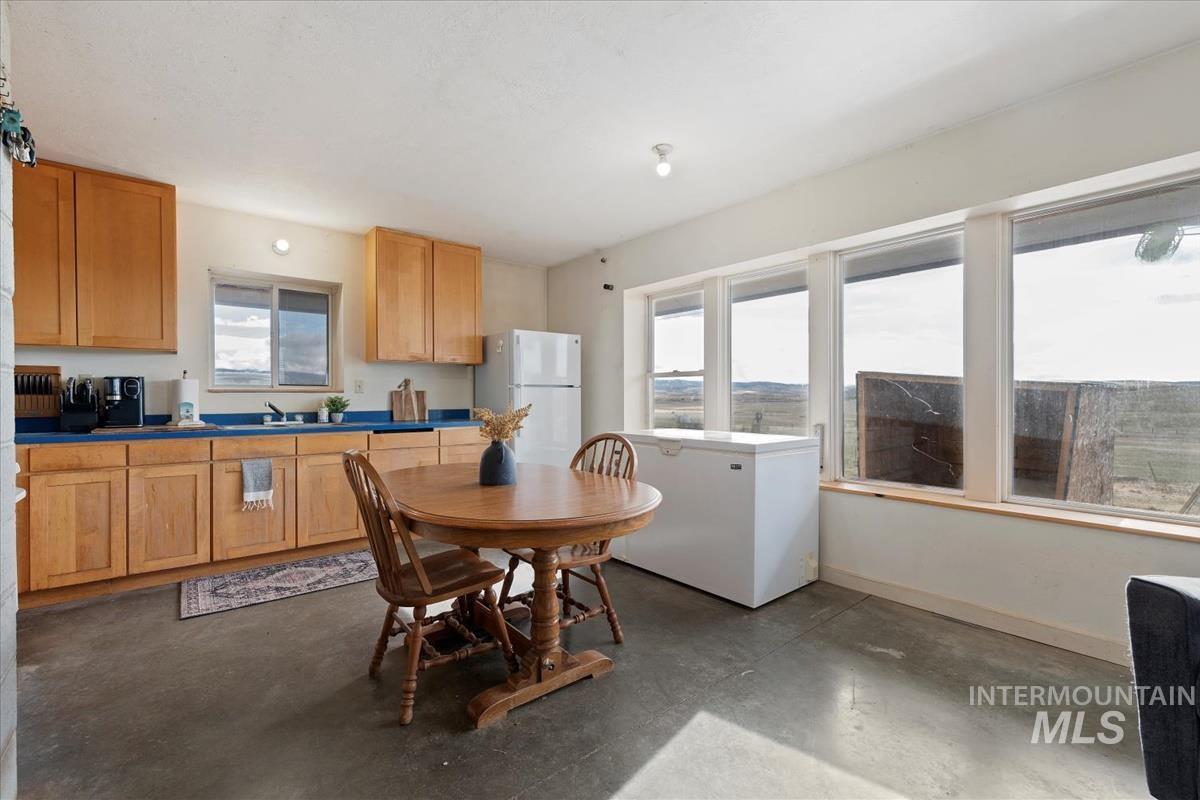 Kitchen with concrete flooring, freestanding refrigerator, fridge, and dark countertops