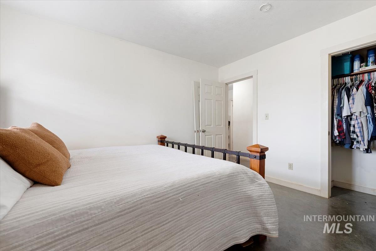 Bedroom with finished concrete flooring and a closet