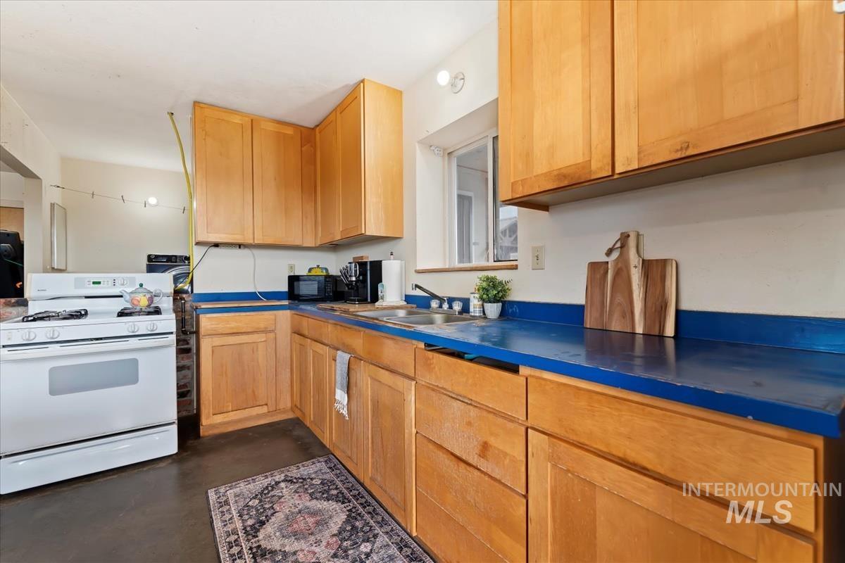 Kitchen with white range with gas cooktop, finished concrete flooring, and dark countertops