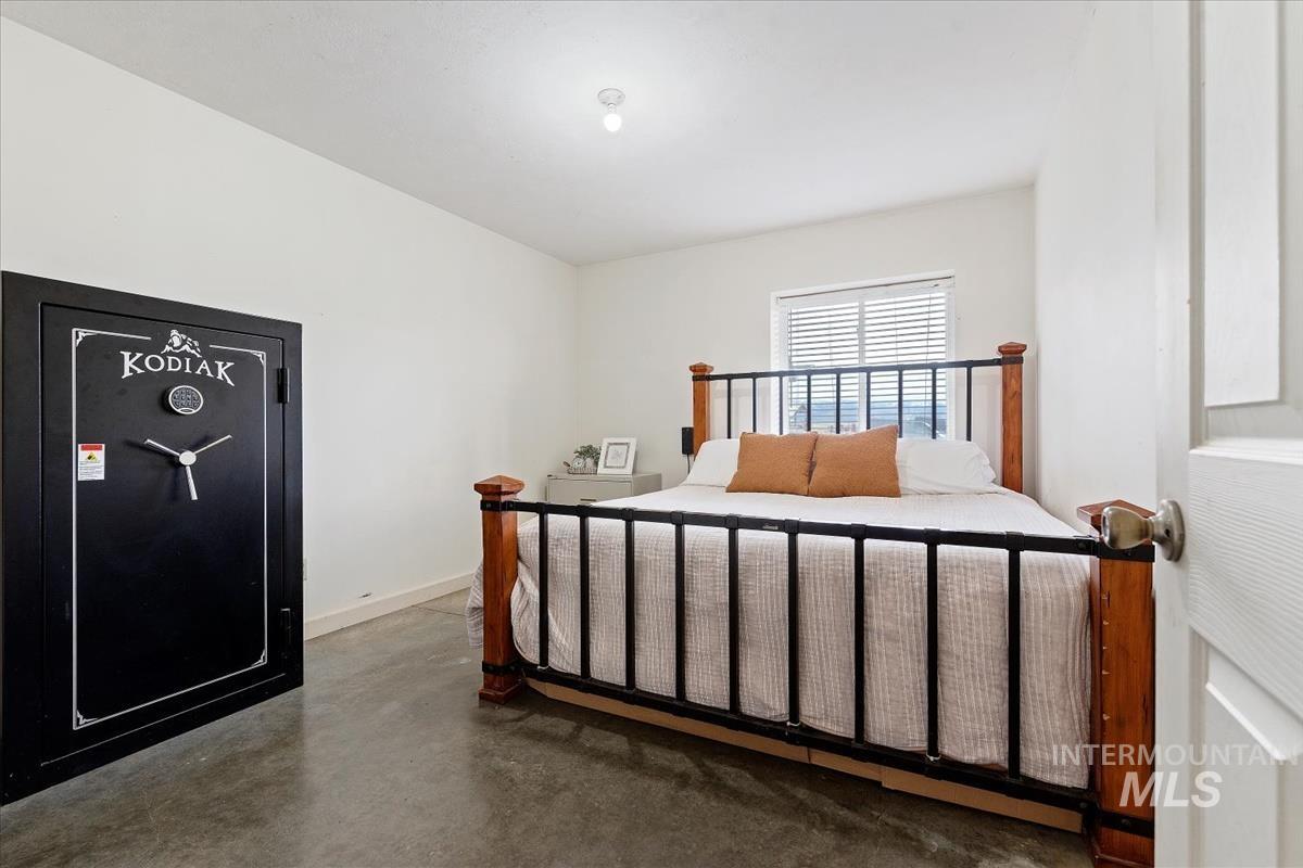 Bedroom with concrete flooring and baseboards