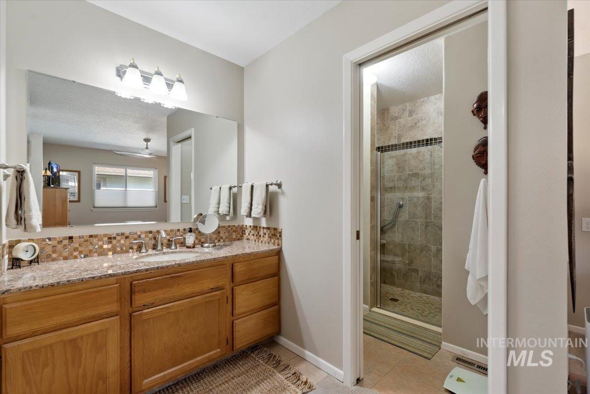 Full bathroom with a shower stall, vanity, light tile patterned floors, a textured ceiling, and ceiling fan