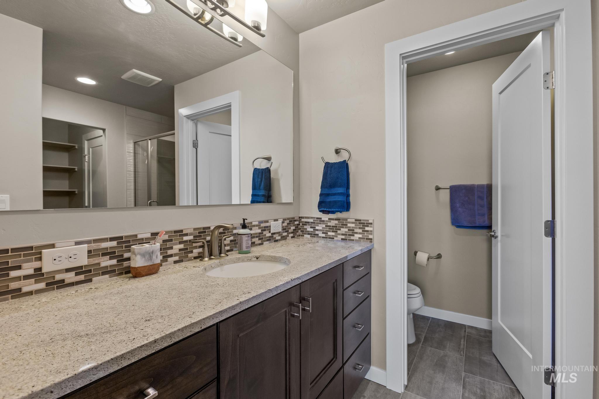 Full bathroom featuring tasteful backsplash, vanity, a stall shower, recessed lighting, and a closet