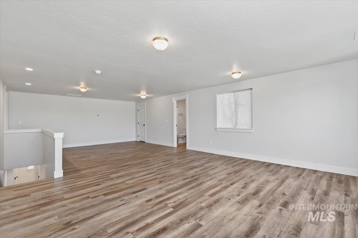 Expansive open-concept room featuring wood-finish flooring, recessed lighting, and flush mount light fixtures