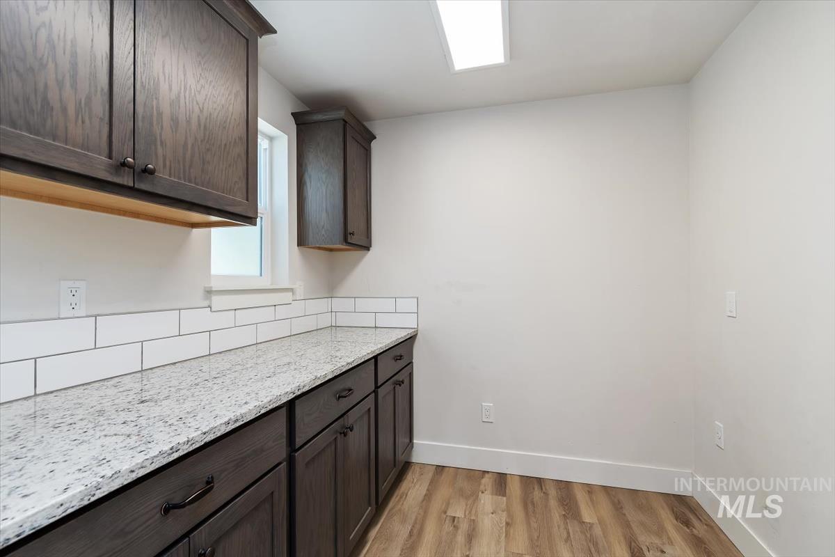 Contemporary kitchen area featuring dark wood-finish cabinetry, light-colored speckled countertops, and a white subway tile backsplash