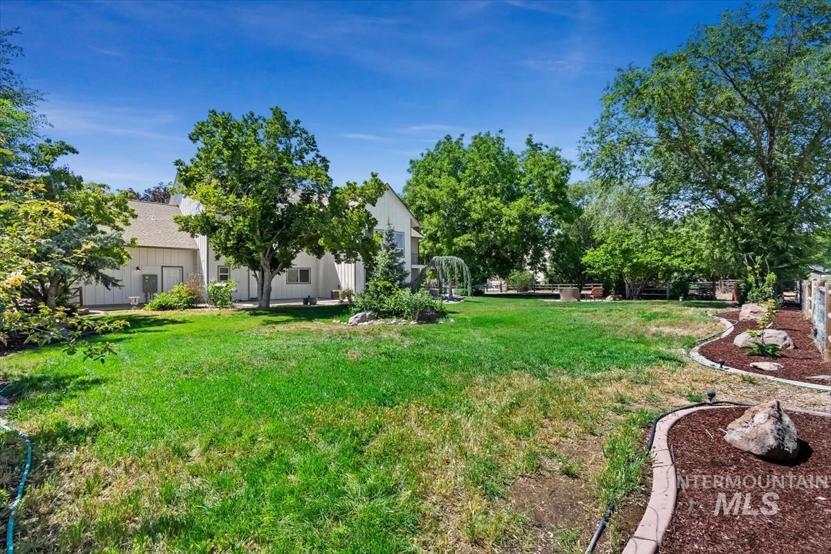 Expansive backyard featuring a large lawn area, mature trees, and landscaping with decorative rock and mulch