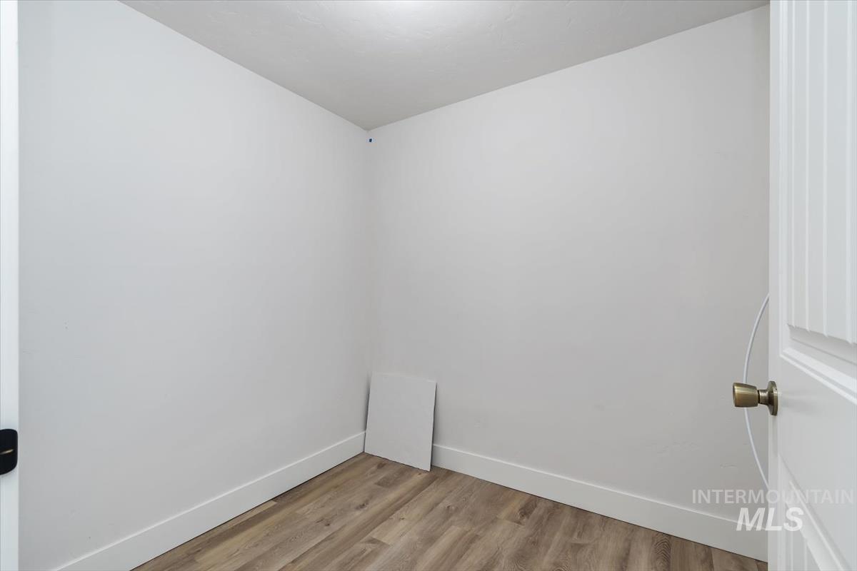 Neutral white walls with wood-finish flooring and white baseboards