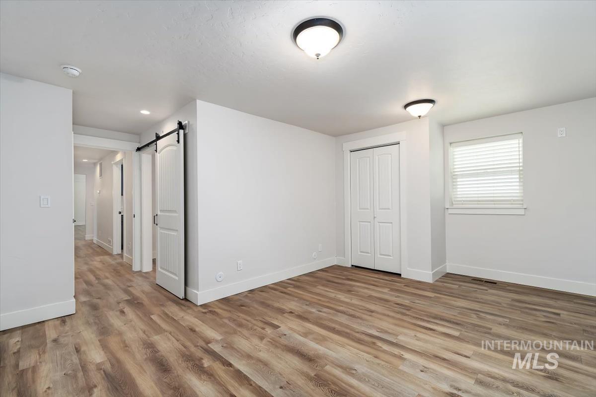 Spacious room with wood-finish flooring, white walls, and bright overhead lighting