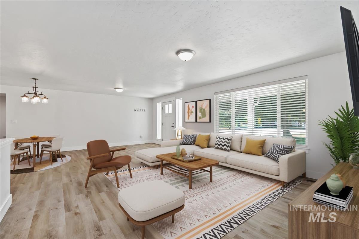 Spacious open-concept living area featuring wood-finish flooring, recessed lighting, and a large front-facing window with horizontal blinds