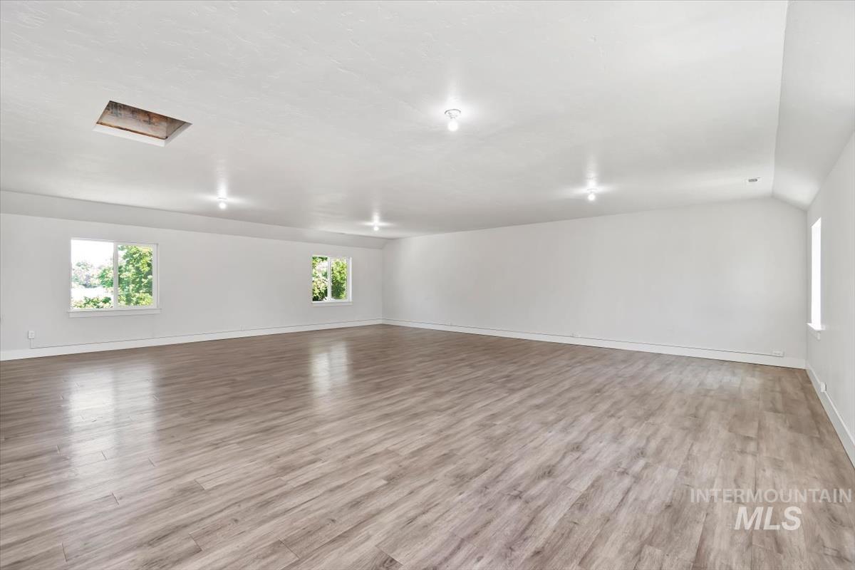 Spacious room featuring wood-finish flooring, multiple windows, recessed lighting, and a neutral color palette