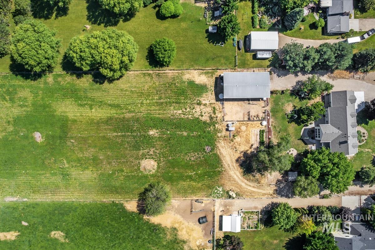 Expansive green space featuring large fields, mature trees, and a substantial outbuilding with a metal roof