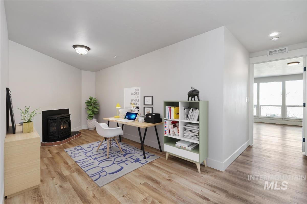 Room featuring wood-finish flooring and a corner fireplace with brick surround