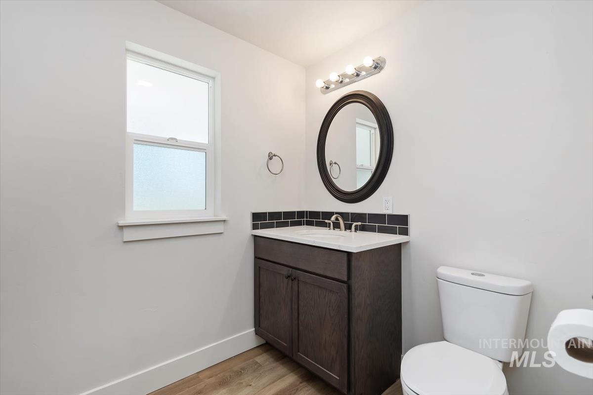 Bathroom featuring a dark wood-finish vanity with an integrated sink, black subway tile backsplash, and an oval framed mirror