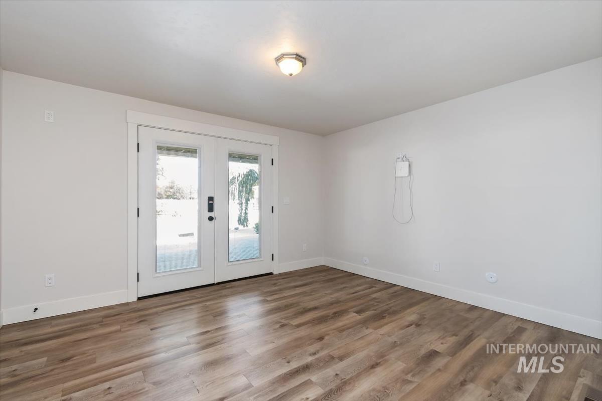 Bright interior space featuring wood-finish flooring, white baseboards, and a neutral wall palette