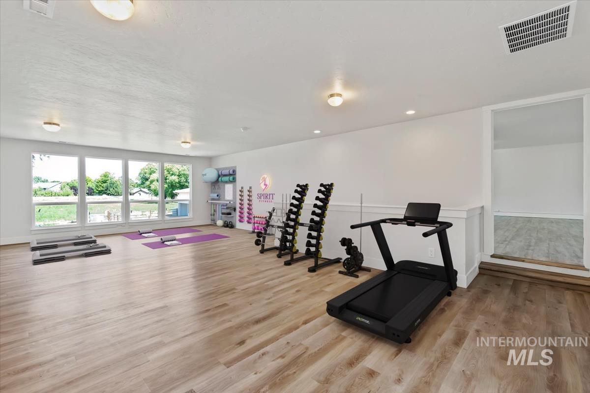 Spacious interior room with wood-finish flooring, white walls, and wainscoting detail