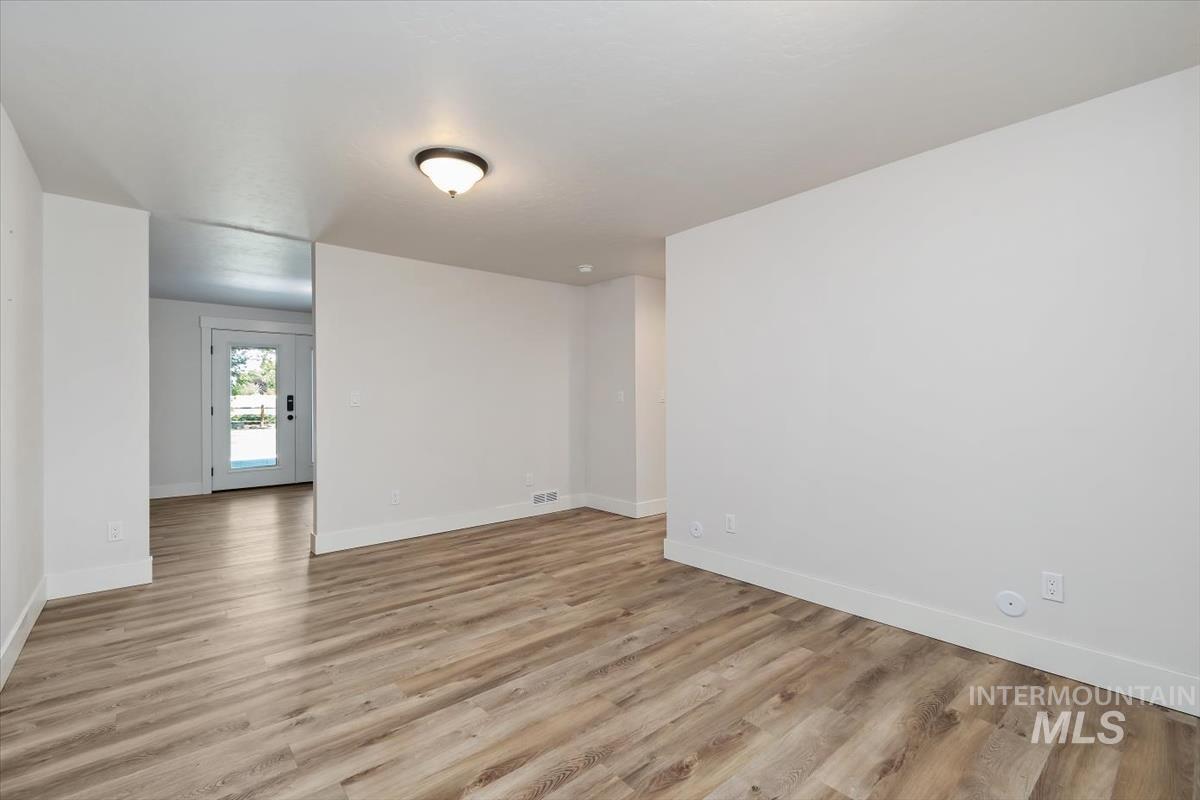 Spacious interior featuring wood-finish flooring, white baseboards, and a semi-flush mount ceiling light