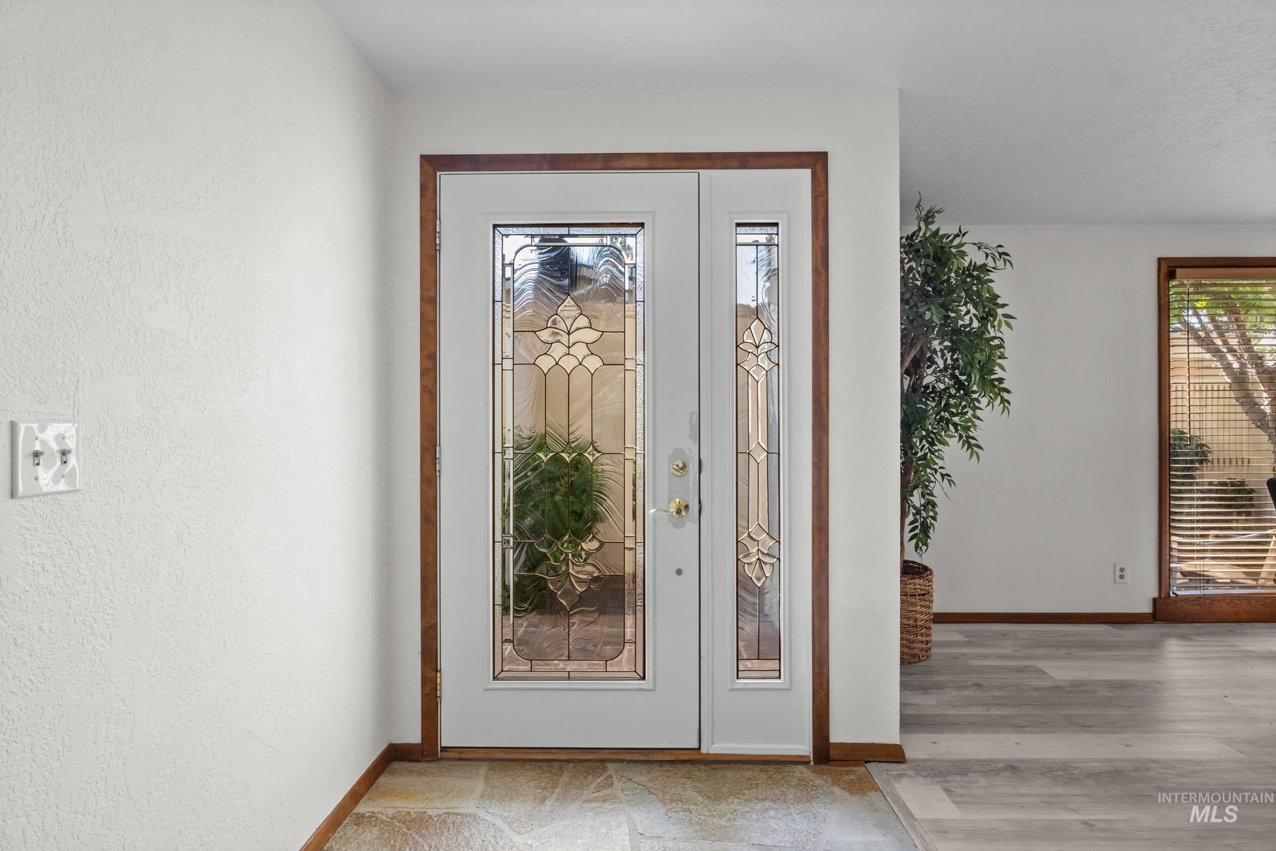 Doorway to outside with baseboards and a textured wall