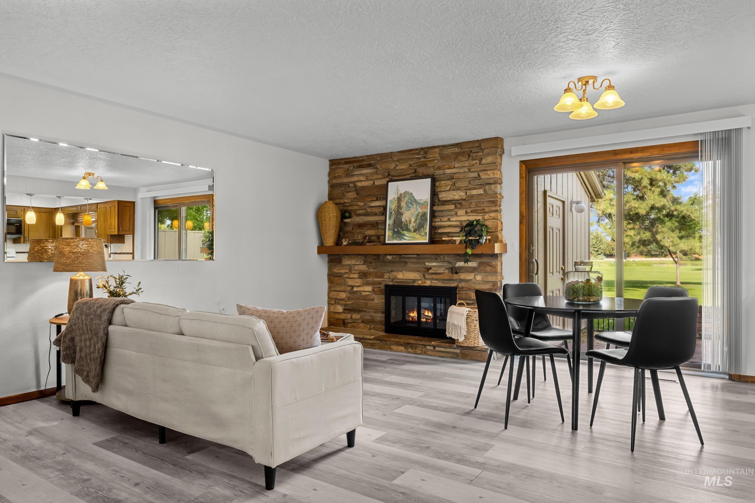 Living area with a textured ceiling, a fireplace, and light wood-type flooring