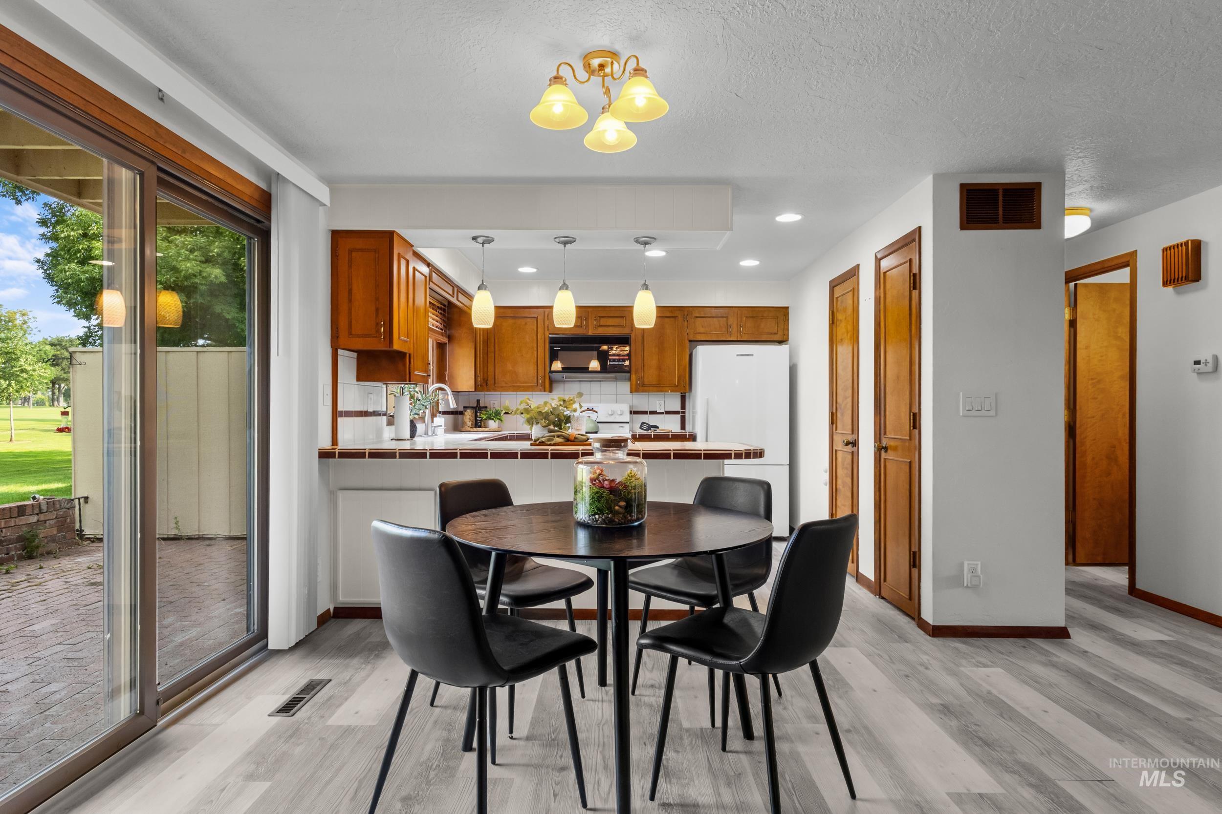 Dining room with light wood-type flooring, recessed lighting, a chandelier, and a textured ceiling