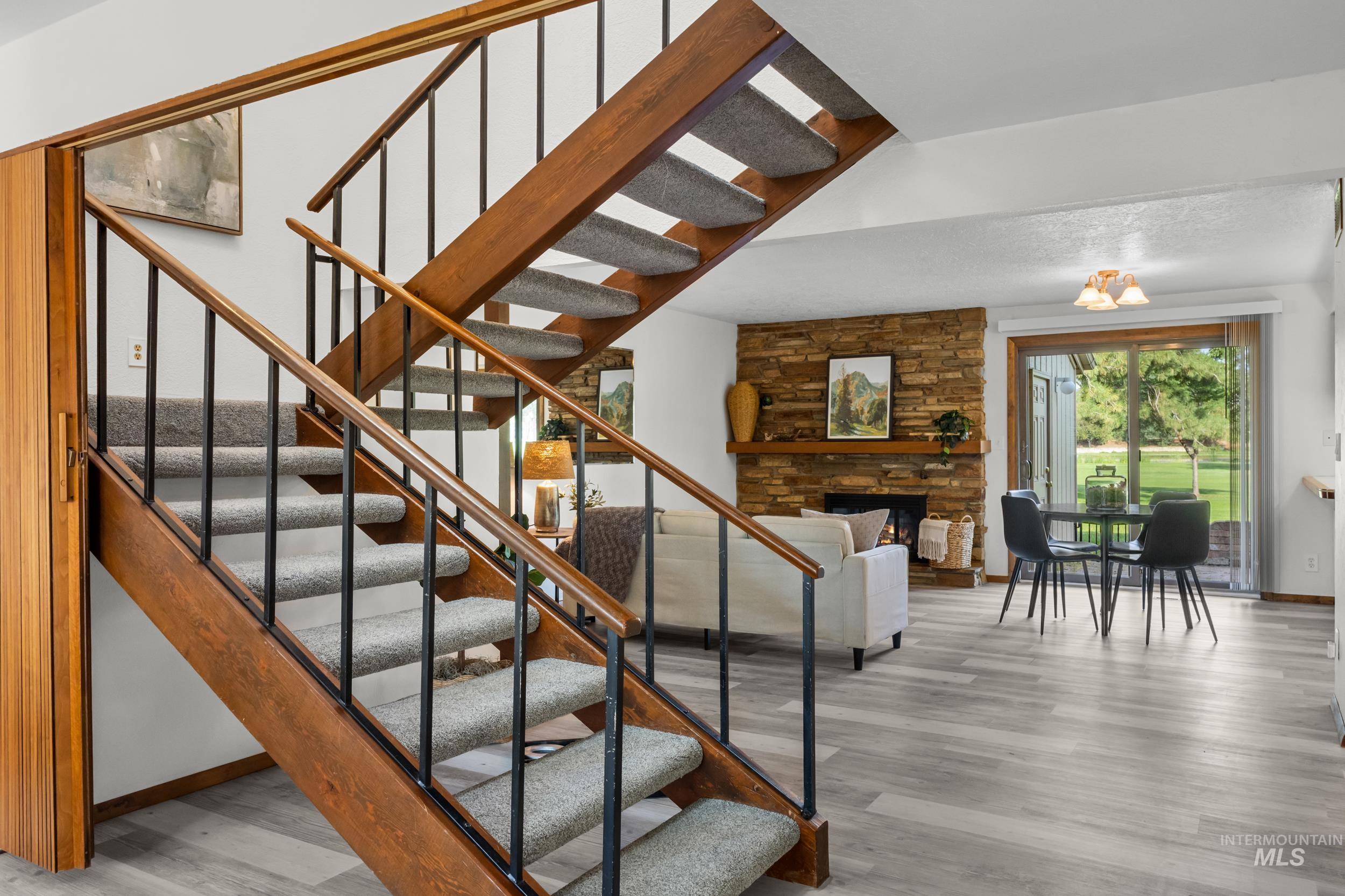 Stairs featuring a stone fireplace and wood finished floors
