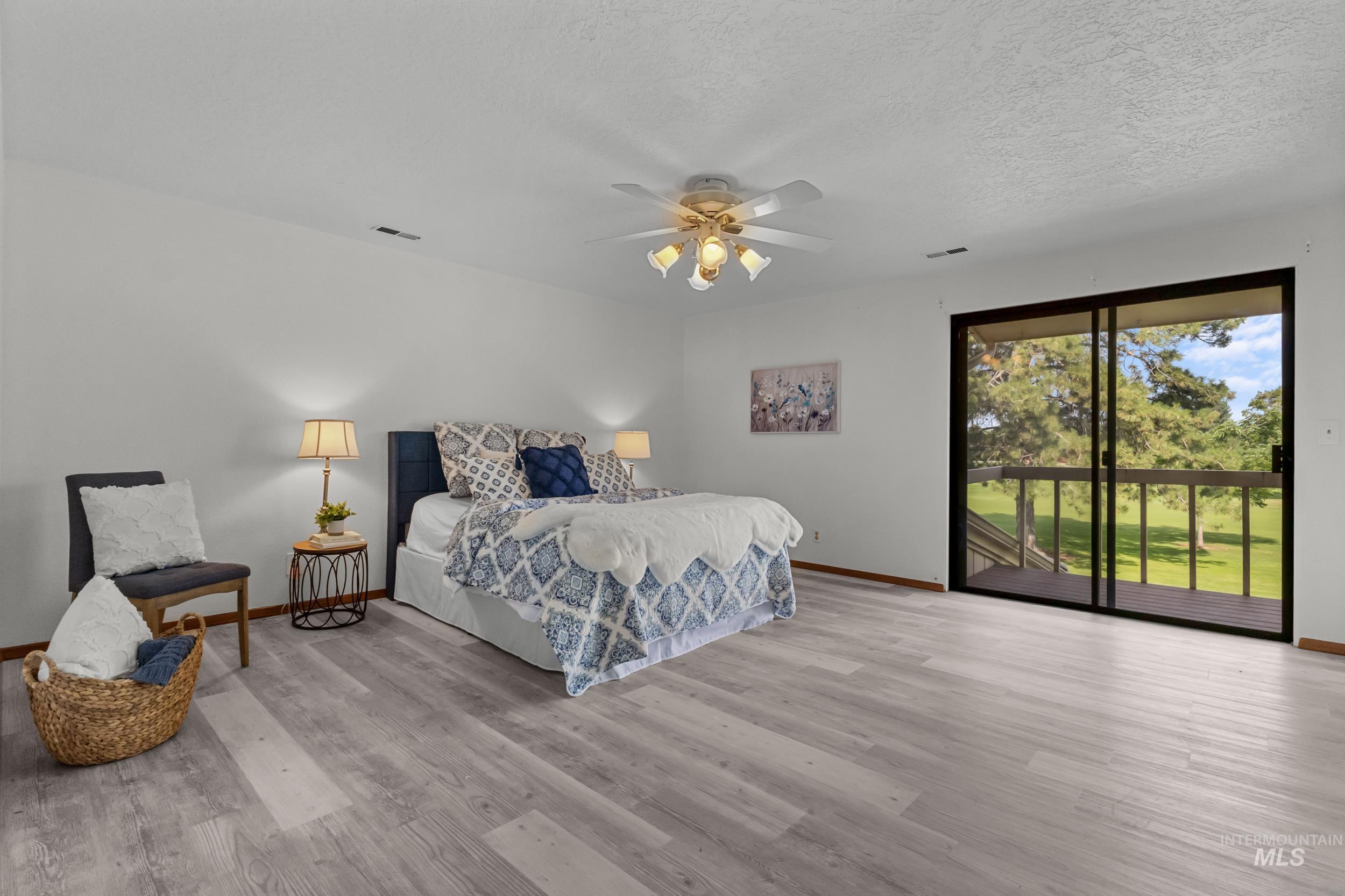 Bedroom featuring access to outside, light wood finished floors, ceiling fan, and a textured ceiling