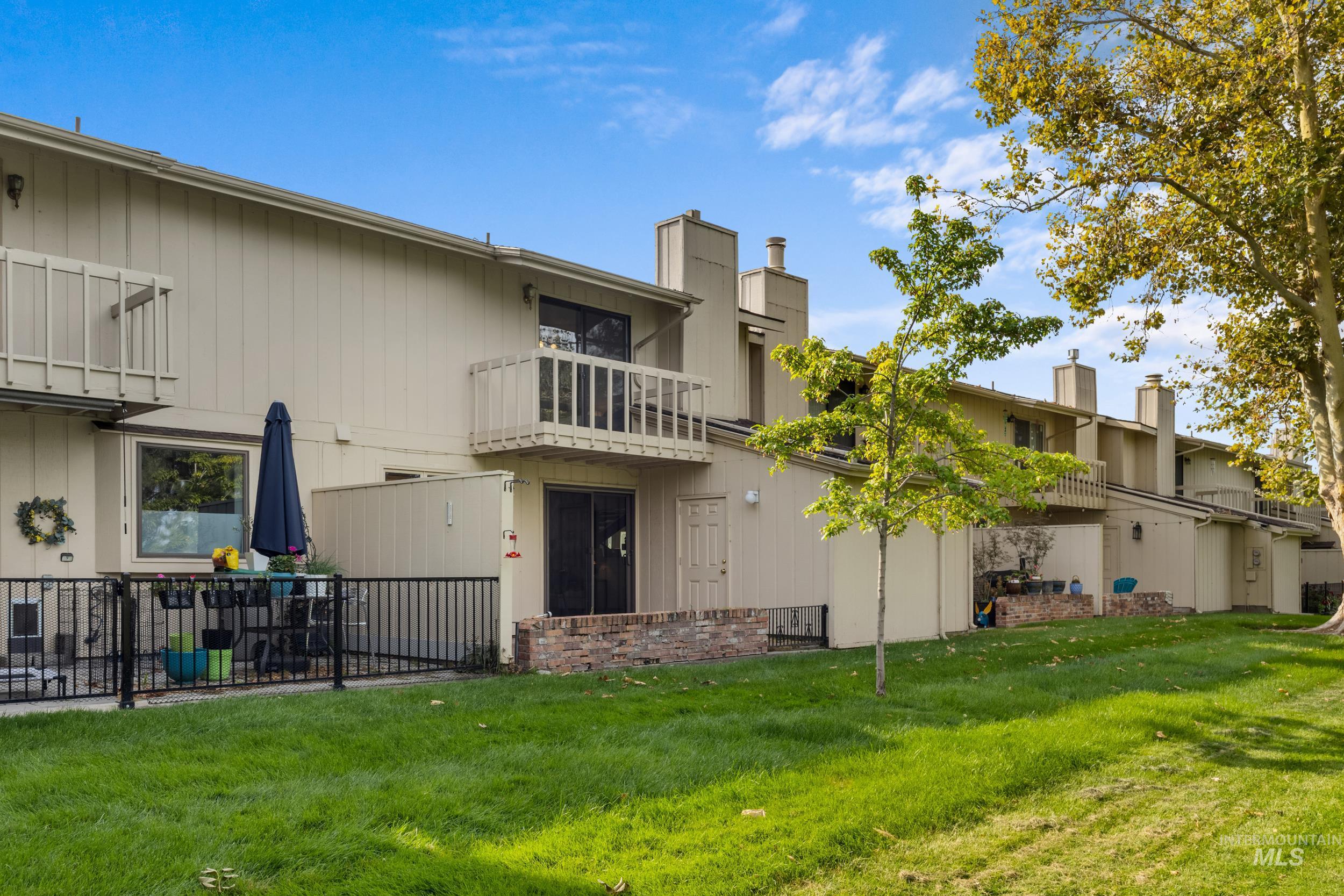 Rear view of house with a balcony, a lawn, and a chimney