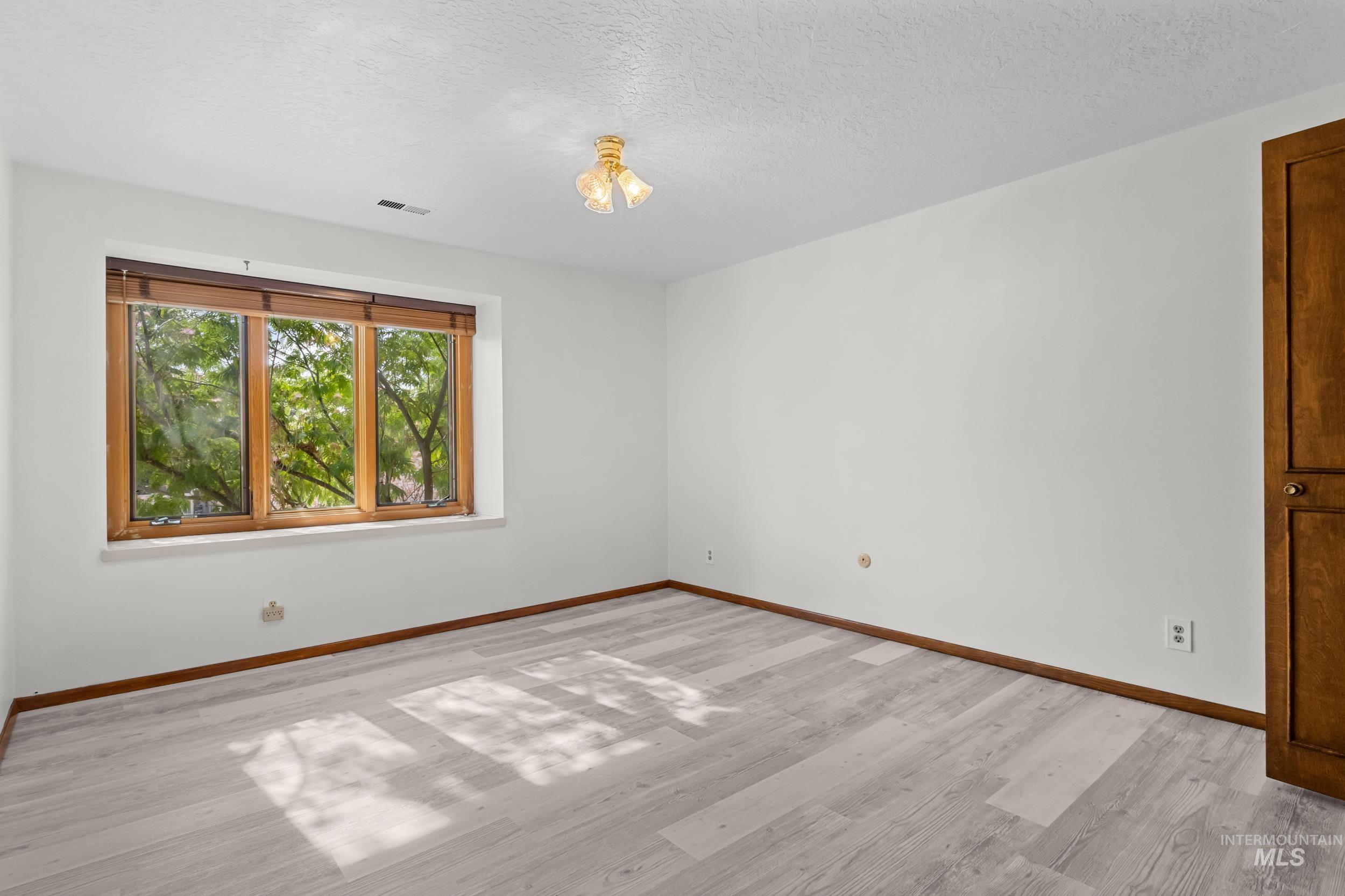 Empty room with a textured ceiling and light wood finished floors