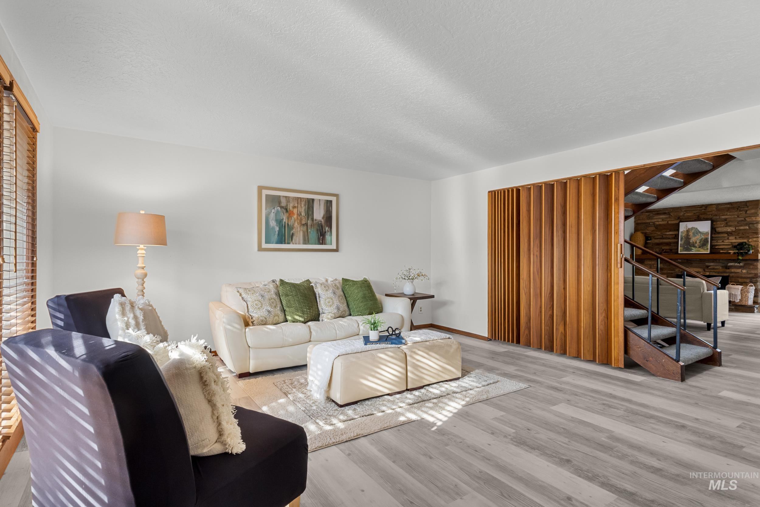 Living room with stairs, wood finished floors, and a textured ceiling