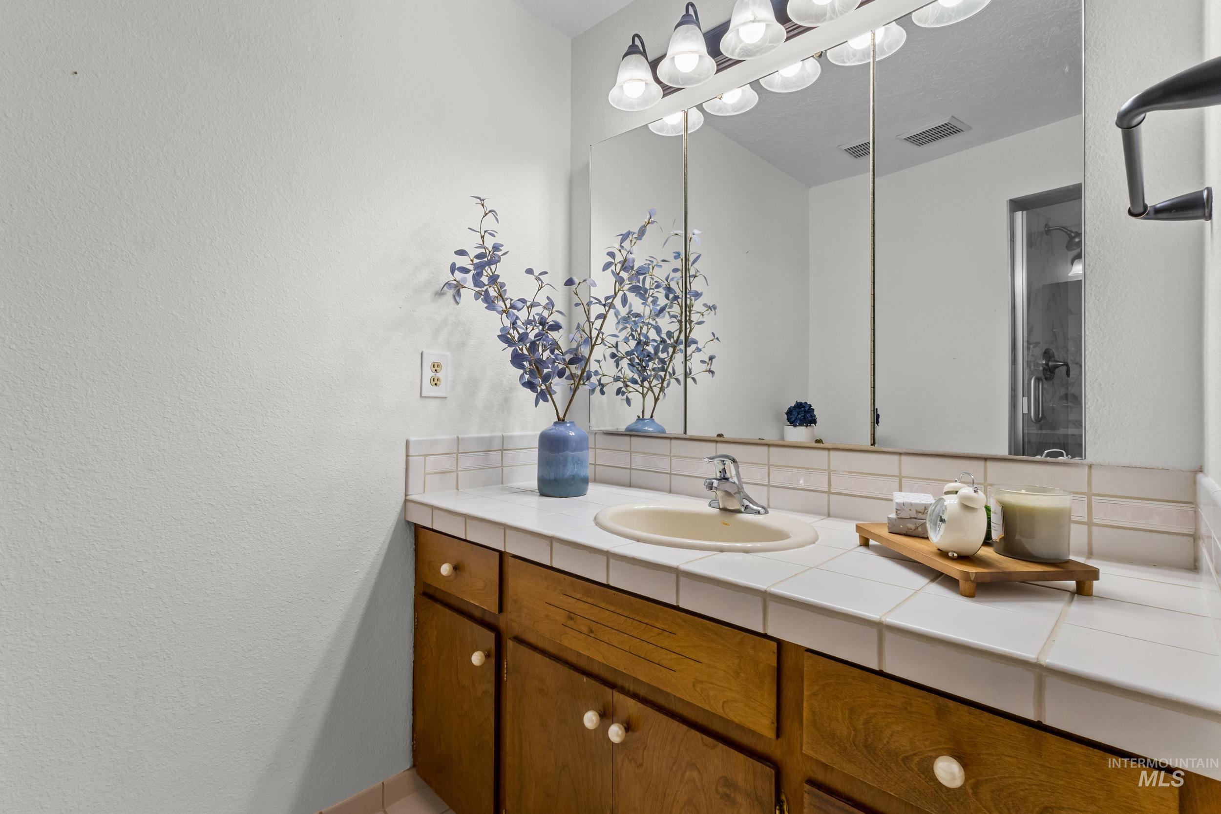 Full bath with vanity, a textured wall, and backsplash
