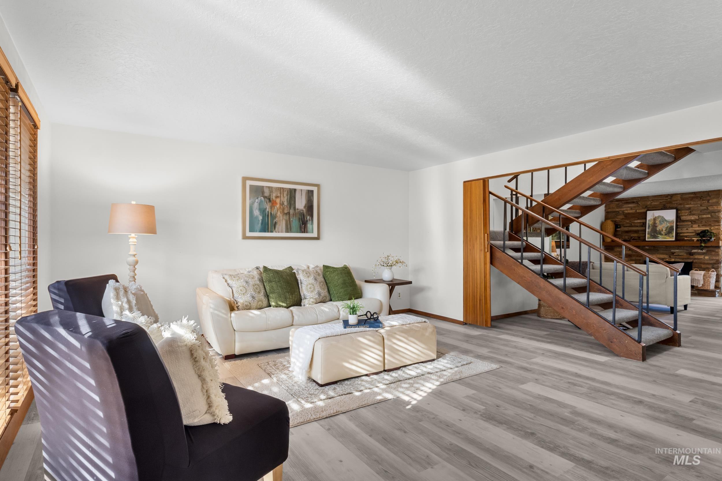 Living room with wood finished floors, stairway, and a textured ceiling