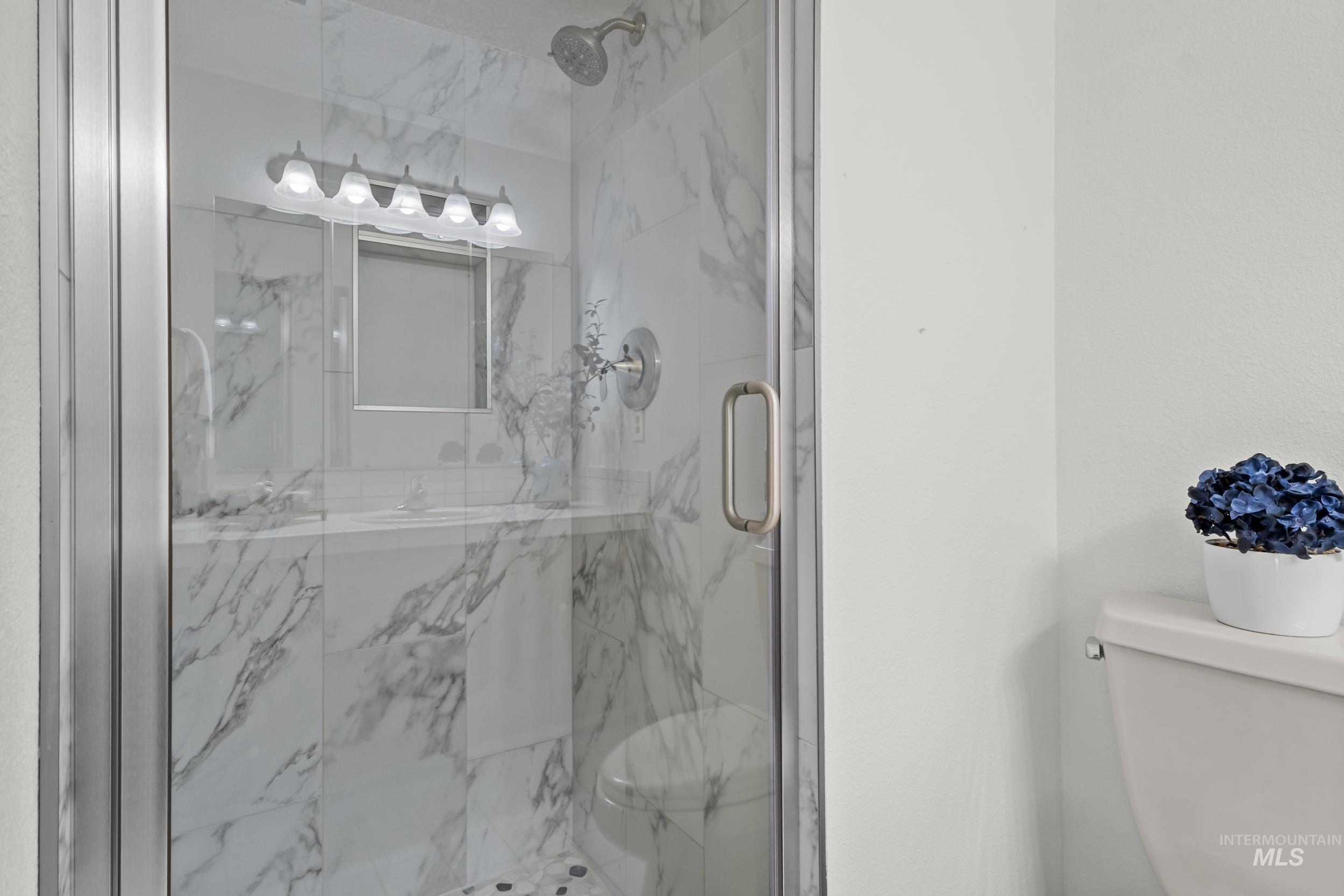 Bathroom featuring toilet and a marble finish shower