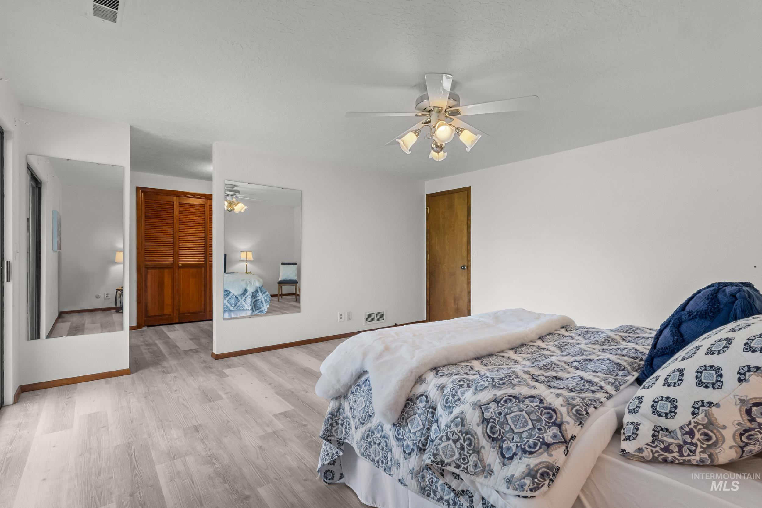 Bedroom with light wood finished floors, ceiling fan, and a closet