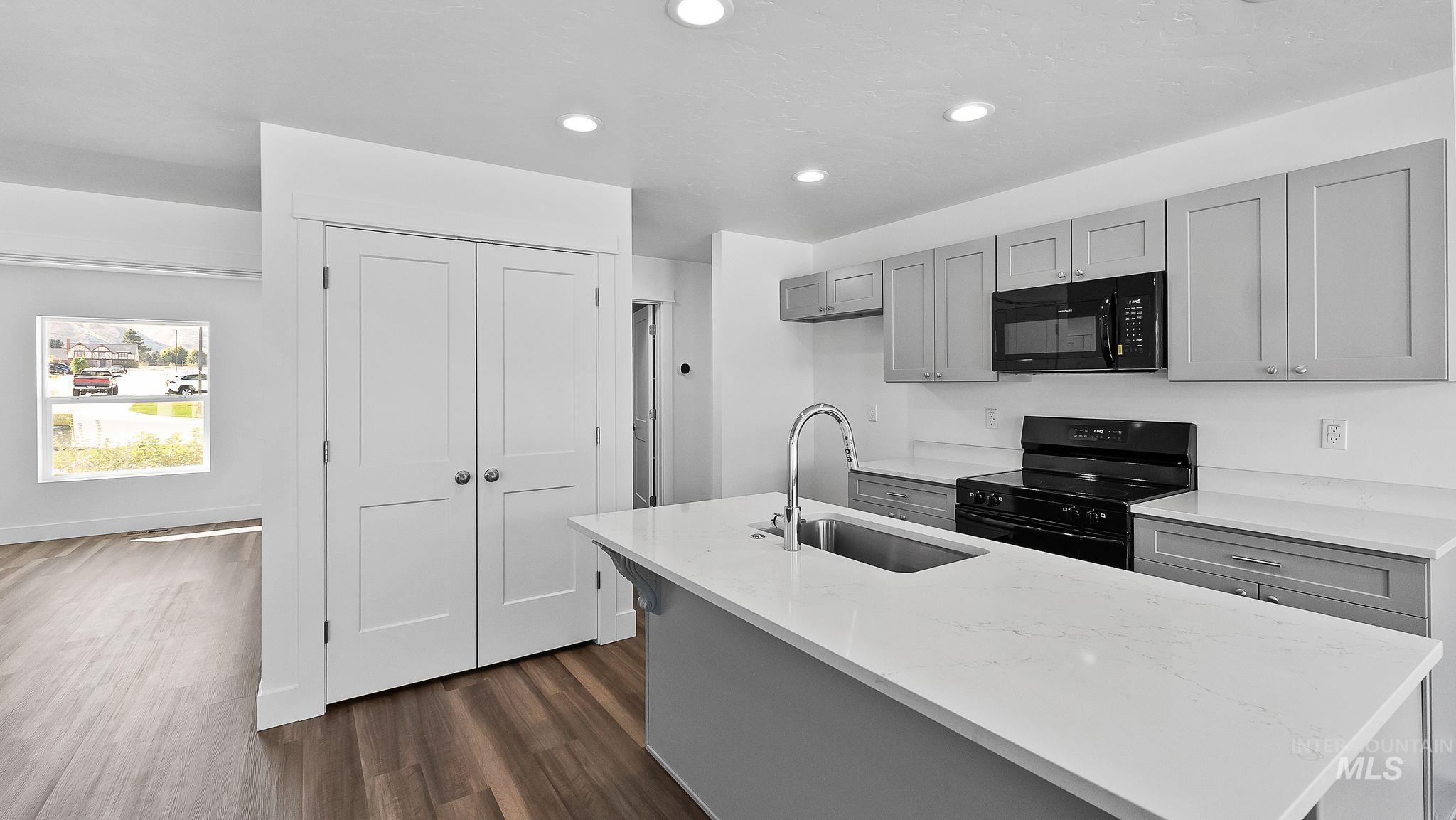Kitchen featuring gray cabinetry, black appliances, dark wood-style floors, recessed lighting, and light stone counters