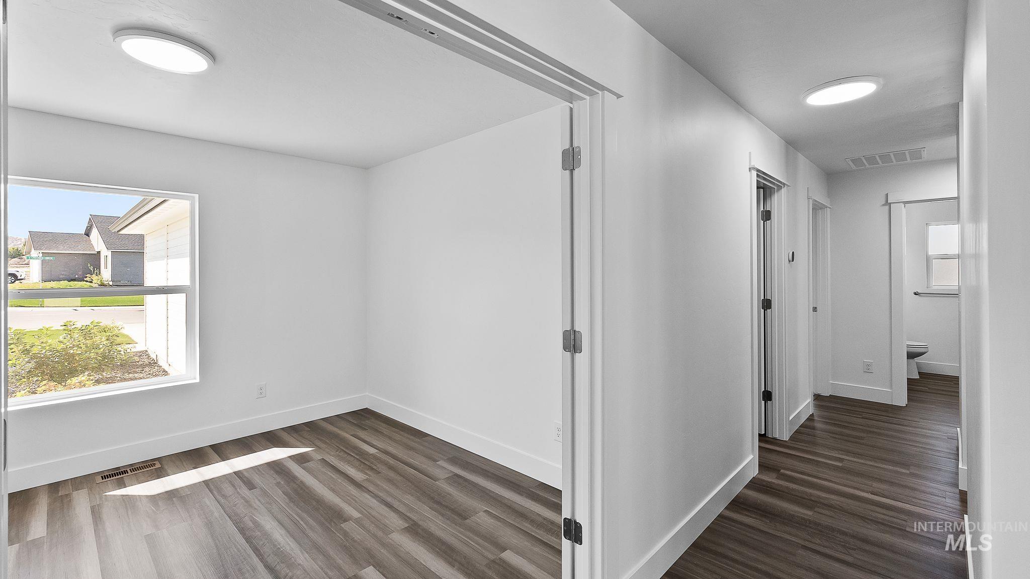 Corridor featuring dark wood-style floors and baseboards