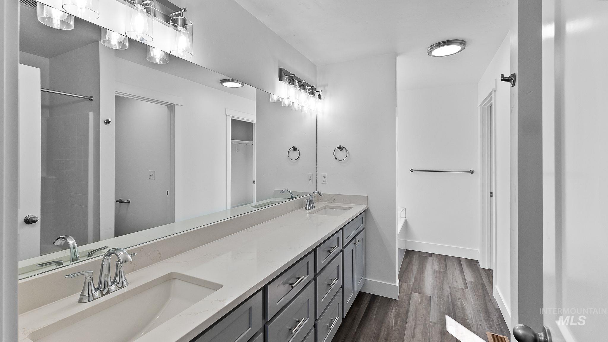 Full bathroom featuring double vanity and dark wood-style floors