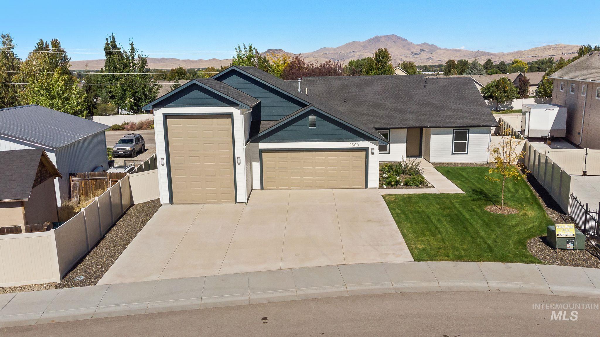 View of front facade featuring a garage, concrete driveway, a mountain view, roof with shingles, and a residential view