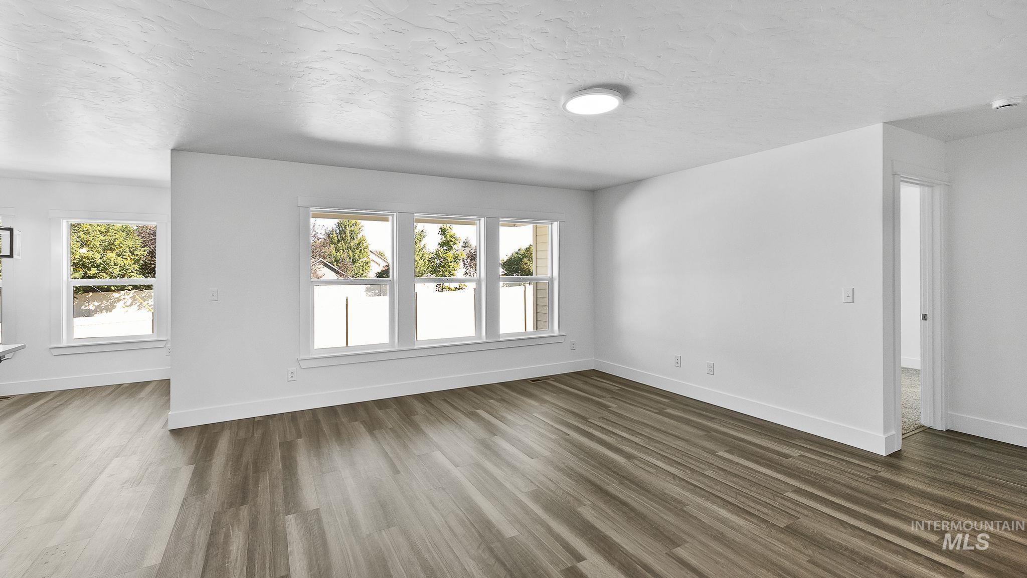 Unfurnished living room with a textured ceiling and dark wood finished floors