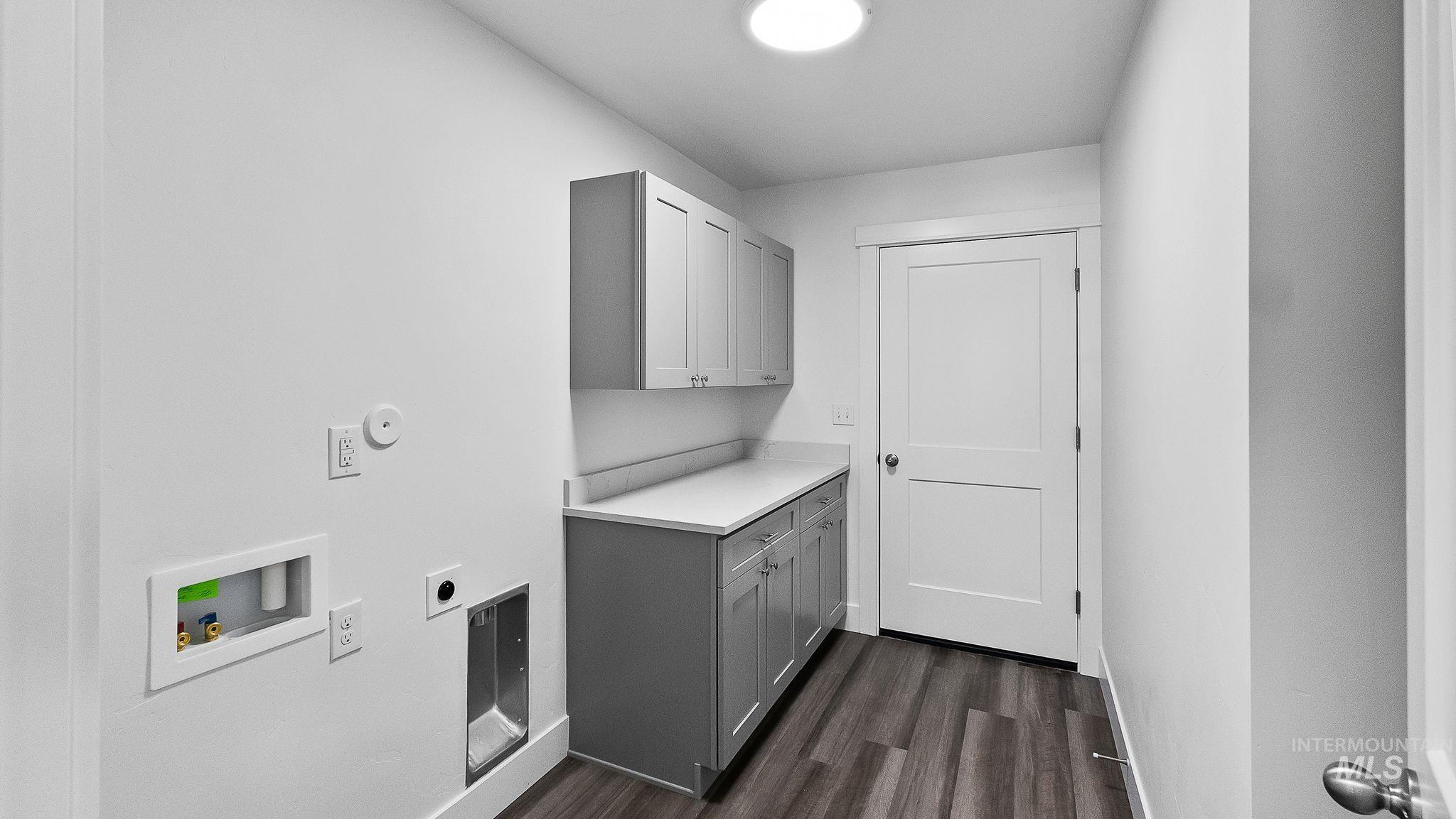 Washroom featuring dark wood finished floors, cabinet space, hookup for a washing machine, and hookup for an electric dryer