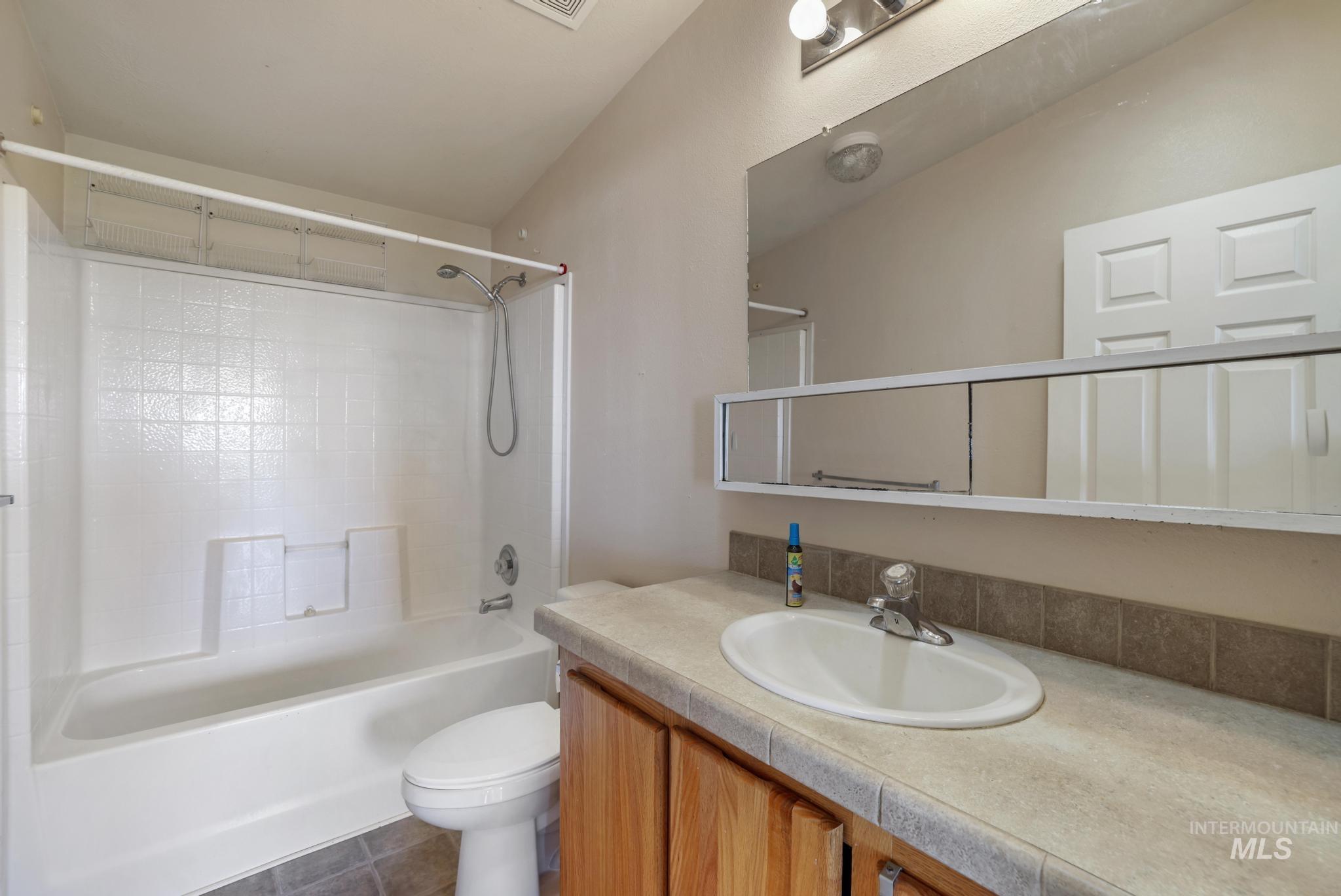 Full bath with shower / bathtub combination, vanity, and dark tile patterned floors