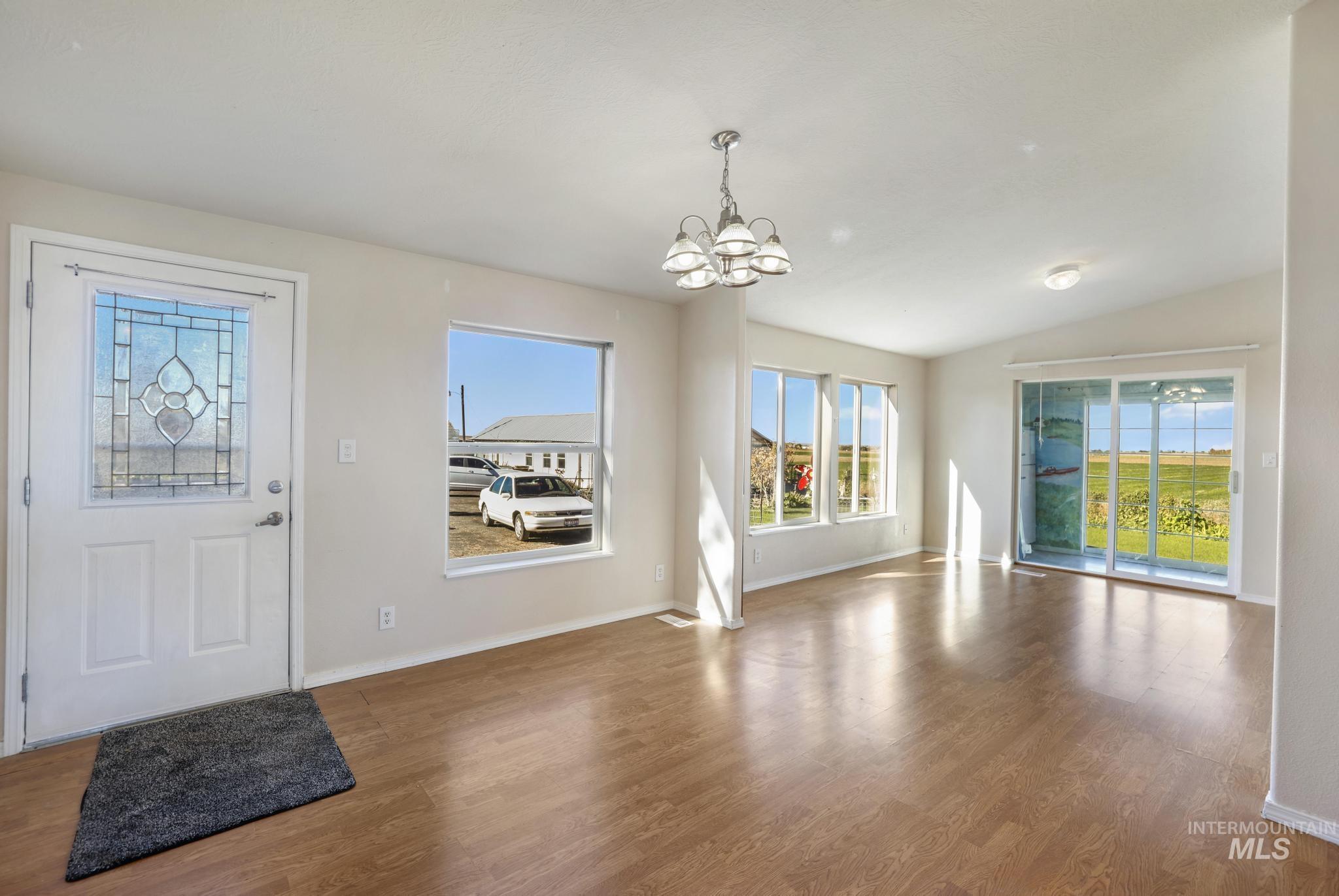 Foyer with wood finished floors, a chandelier, and lofted ceiling