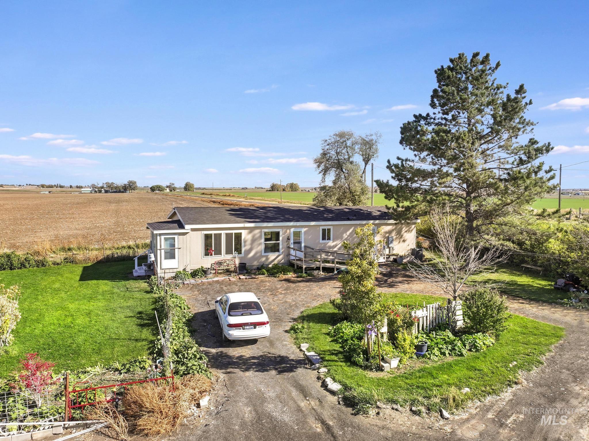 Single story home with dirt driveway, a front yard, and a rural view