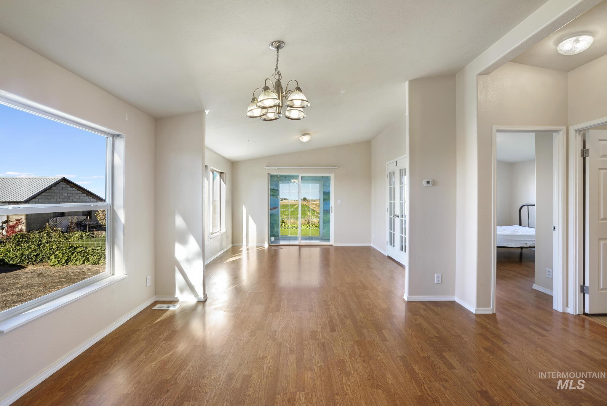 Unfurnished dining area featuring wood finished floors, a chandelier, and vaulted ceiling