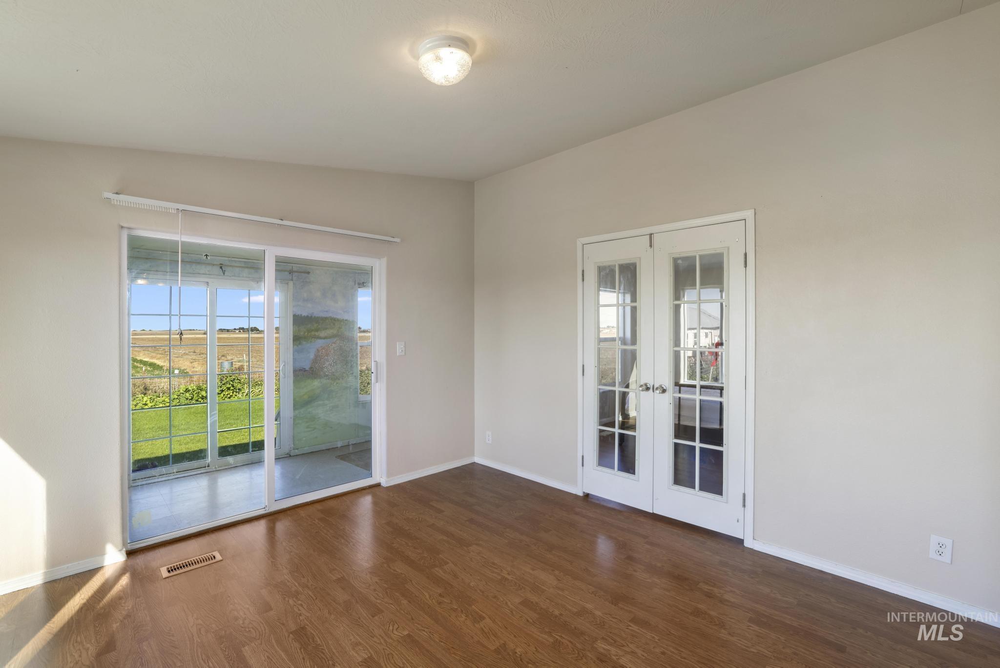Unfurnished room with french doors, dark wood-style floors, and plenty of natural light