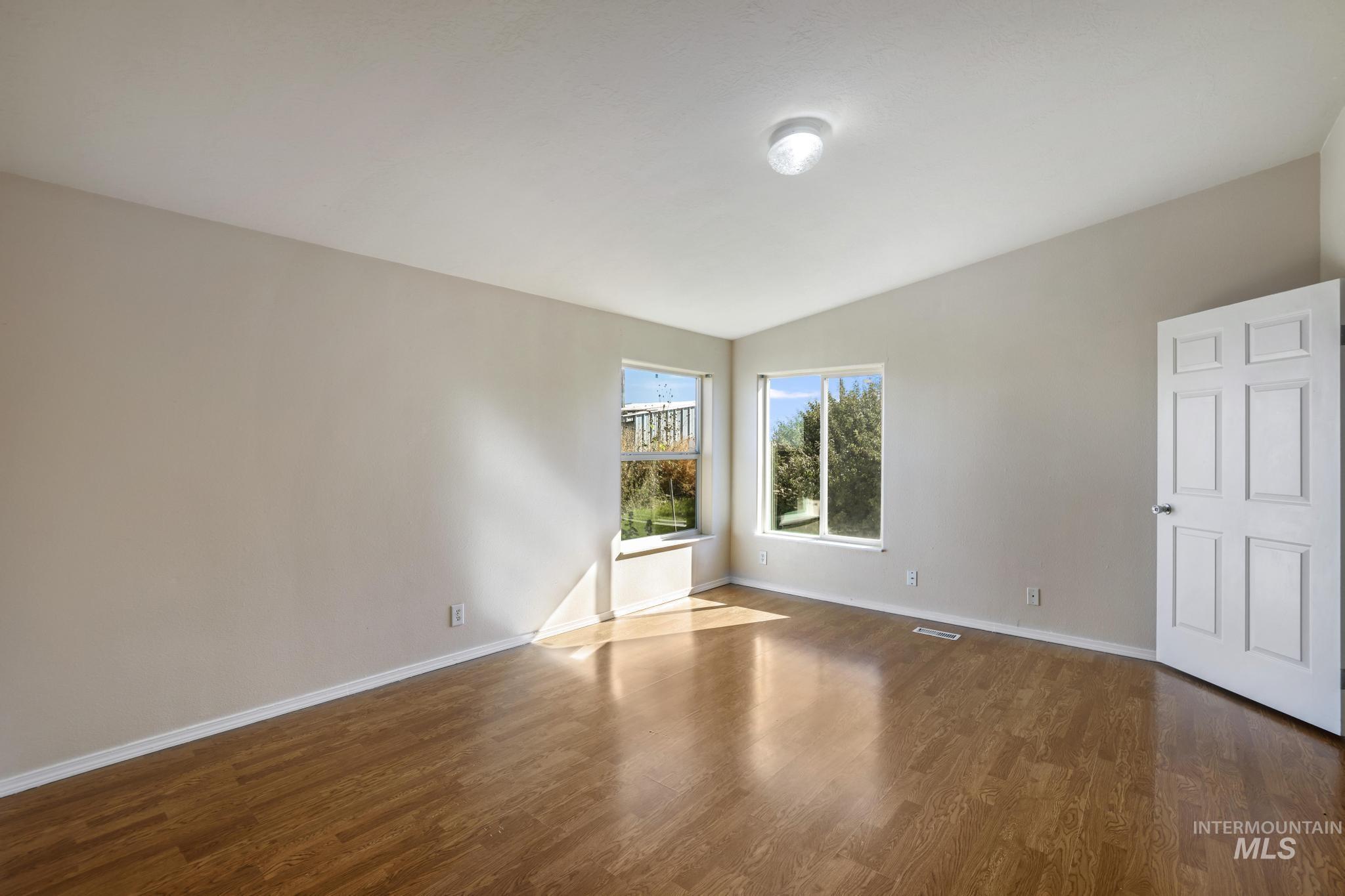 Spare room featuring dark wood-type flooring and lofted ceiling