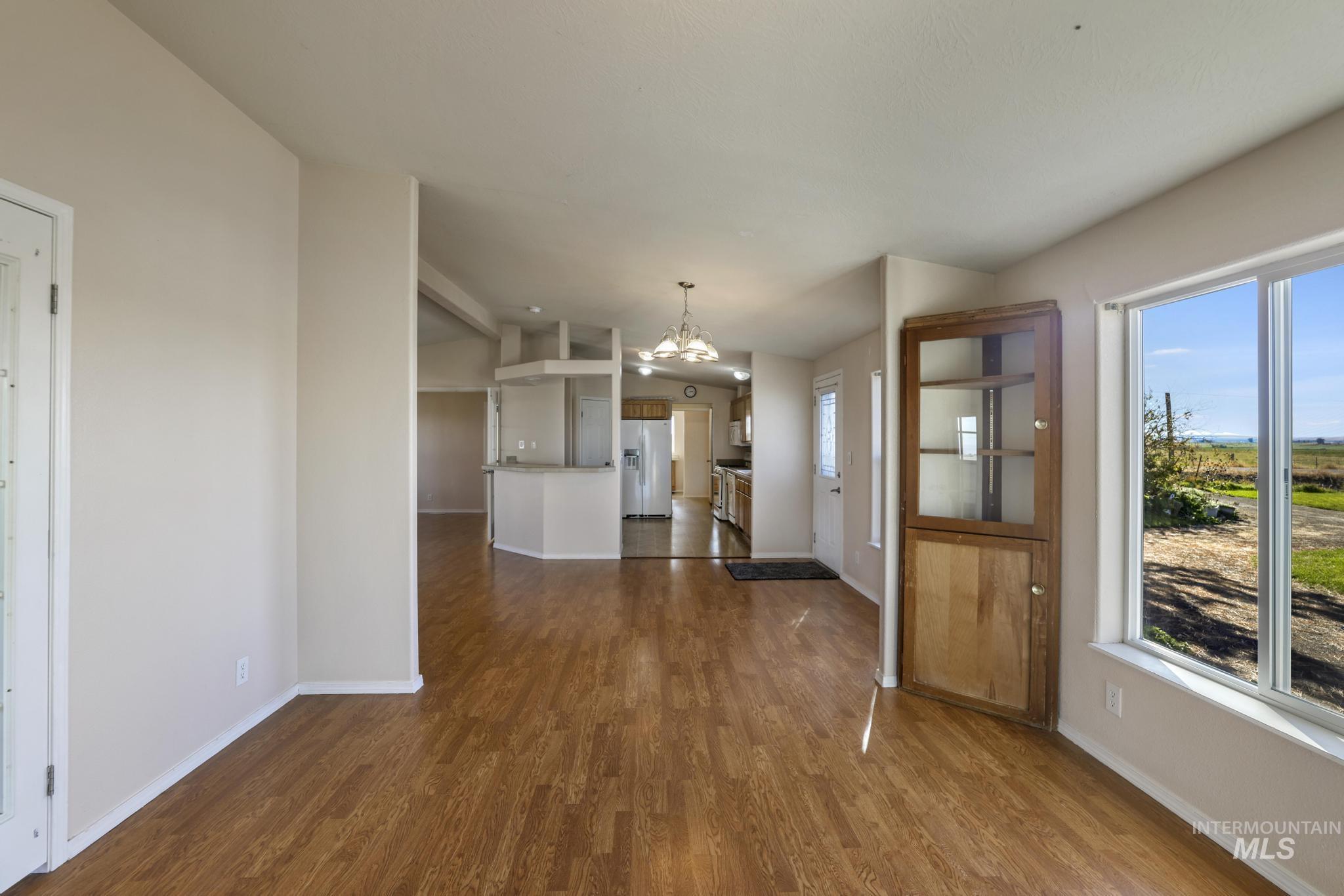 Unfurnished dining area featuring a chandelier, dark wood-style flooring, and lofted ceiling