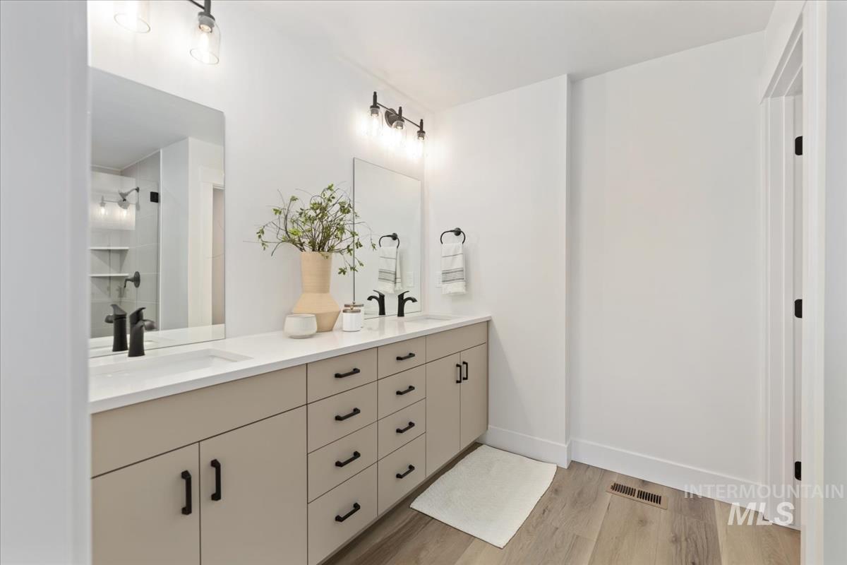 Bathroom with wood finished floors, double vanity, and a shower