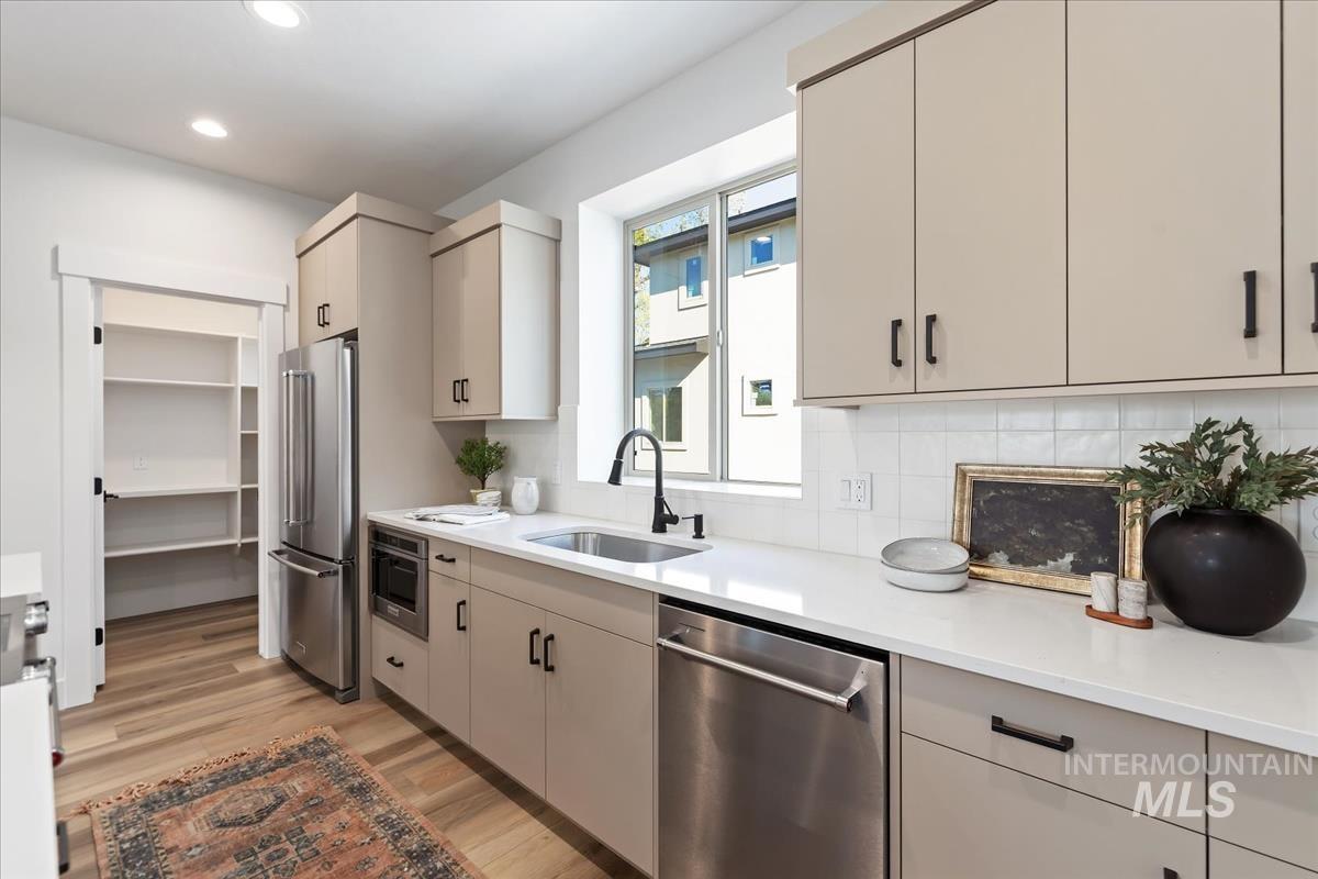 Kitchen featuring stainless steel appliances, light wood-style floors, light countertops, decorative backsplash, and recessed lighting